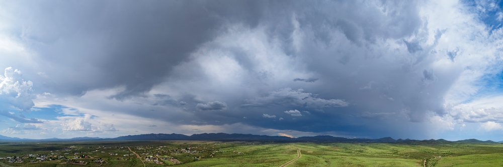 Storm clouds gather over the green landscape, signalling an approaching Monsoon rain with mountains in the background, Storm Chasing, Weather, Environment, Tombstone, Arizona, USA.