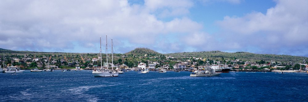 Puerto Baquerizo Morena coastal town with boats and ships anchored in the harbor under a partly cloudy sky, Puerto Baquerizo Morena Galapagos Islands, Ecuador.
