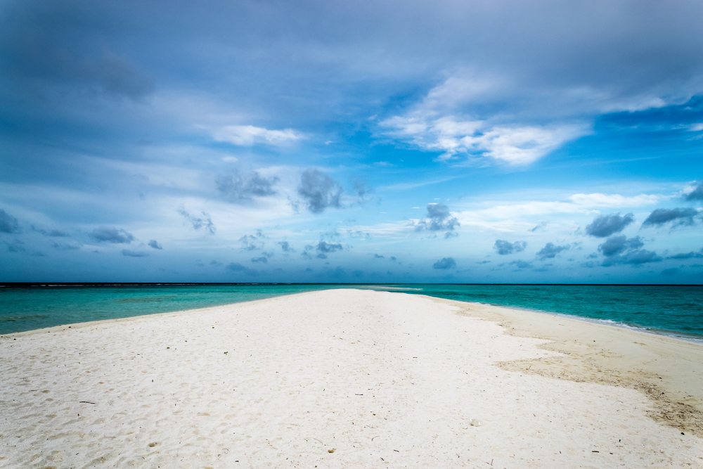 Sandbar with white sand extending into turquoise ocean under a partly cloudy sky, summer, Holliday, travel, landscape, Maldives.