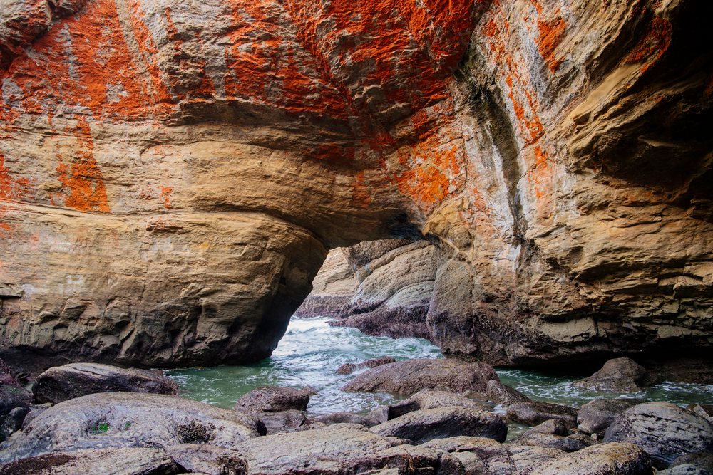 Rock arch formation at Devils Punch bowl with ocean water and rocky shoreline along the Oregon coast, USA.