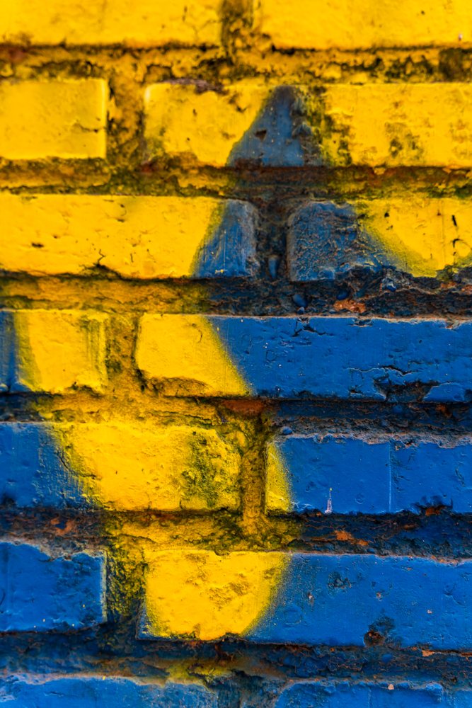 Close-up of a textured brick wall painted blue and yellow, texture, abstract texture, background, wallpaper, Spain.