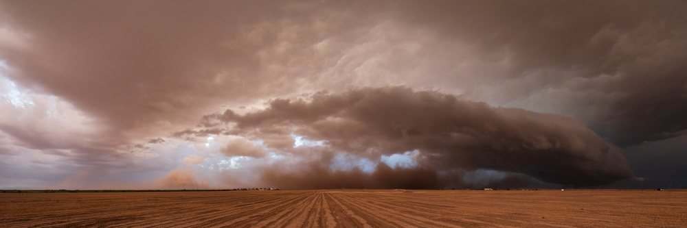 Supercell thunderstorm with dark storm clouds and dust storm advancing over a plowed field, Garden City, Texas, USA.