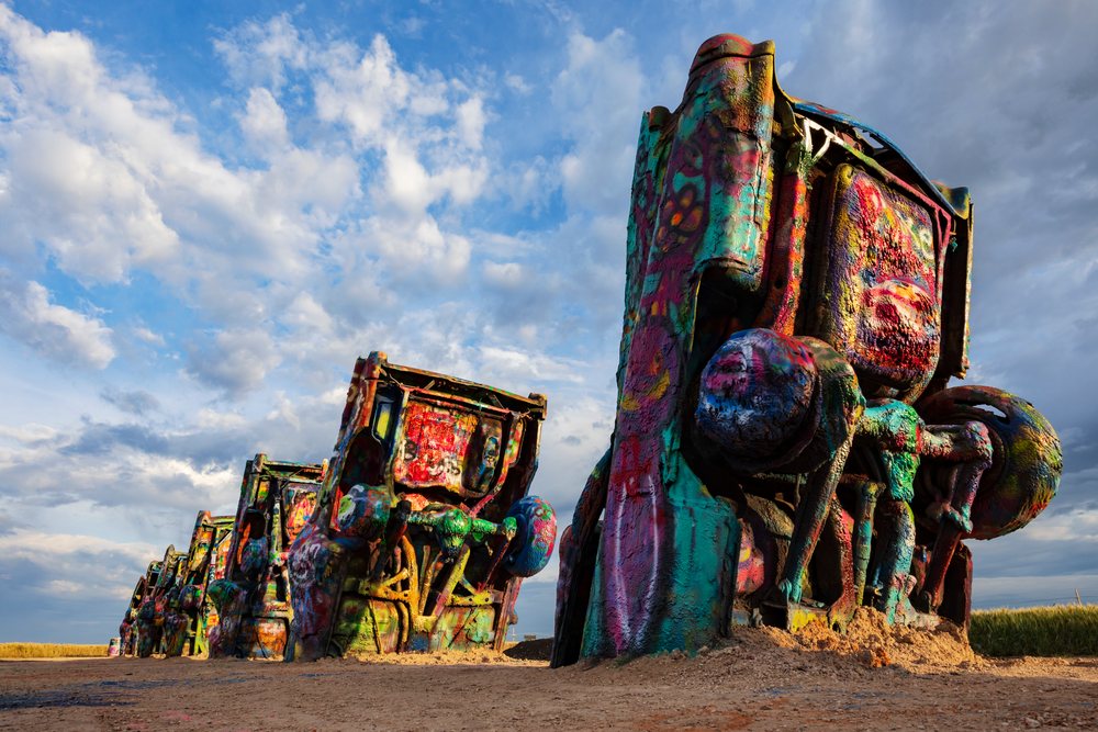 Colorful graffiti-covered Cadillac cars stand upright in a desert setting, at Sunrise, Storm Chasing, Amarillo, Texas, USA.
