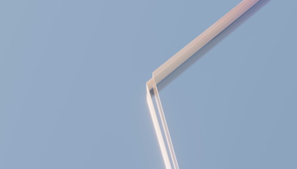 Close-up view of the sharp corner of a transparent glass pane against a blue background.
