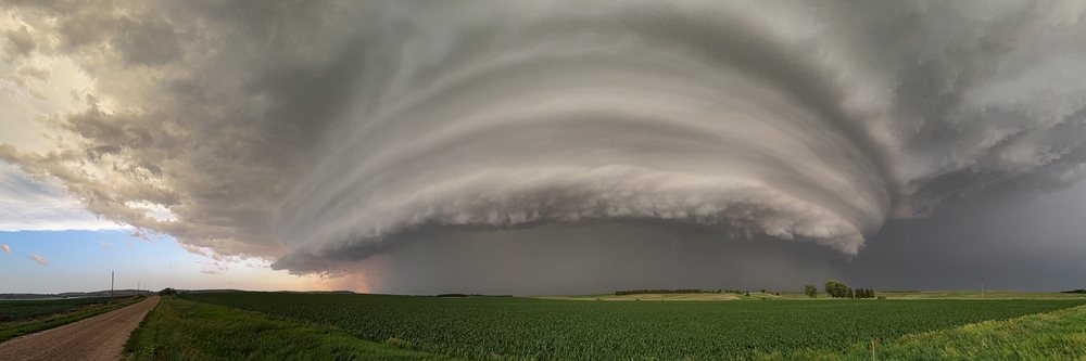 Supercell thunderstorm with layered clouds forming over a green agricultural field during tornado warning conditions, Storm Chasing, Ord, Nebraska, USA.