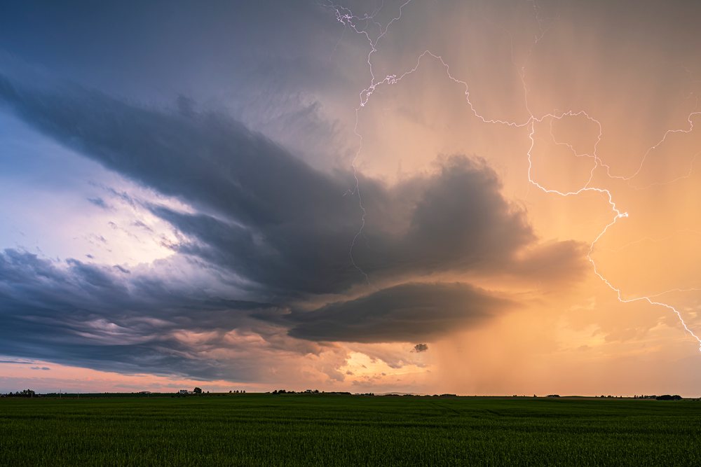 Storm ejects its final burst of Lightning over a green field at sunset, Storm Chasing, Weather, Environment, Rocky View County, Alberta, Canada.