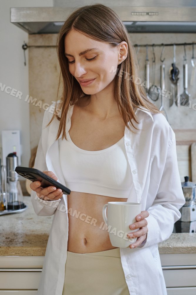A white woman enjoys her morning with coffee and texting