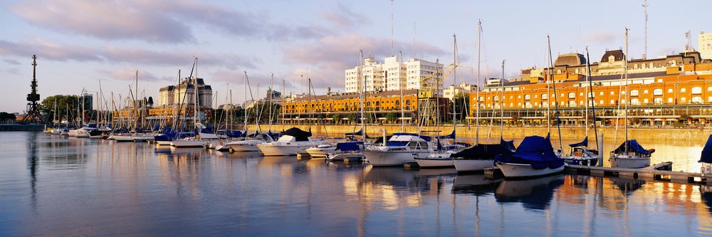 Boats and sailboats moored at a marina with orange brick buildings along the Puerto Madero waterfront in Buenos Aires, in afternoon sunlight, Puerto Madero Buenos Aires, Argentina.