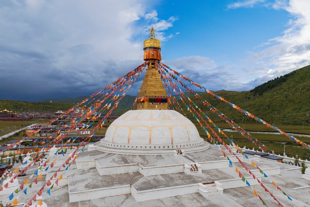 Zhuqing Wujian Zen Forest Monastery Stupa with colorful prayer flags on a mountain grassland in Kham Tibet, China, Sechuan Province, People's Republic of China.