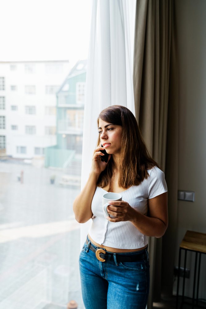 Young woman holding coffee talking on phone