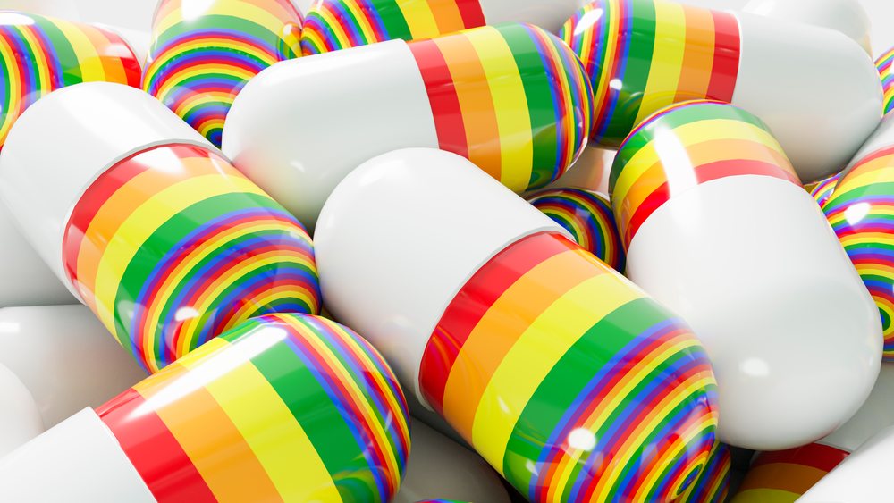 Close-up of clustered white pharmaceutical capsules decorated with vibrant rainbow stripes on a glossy surface.