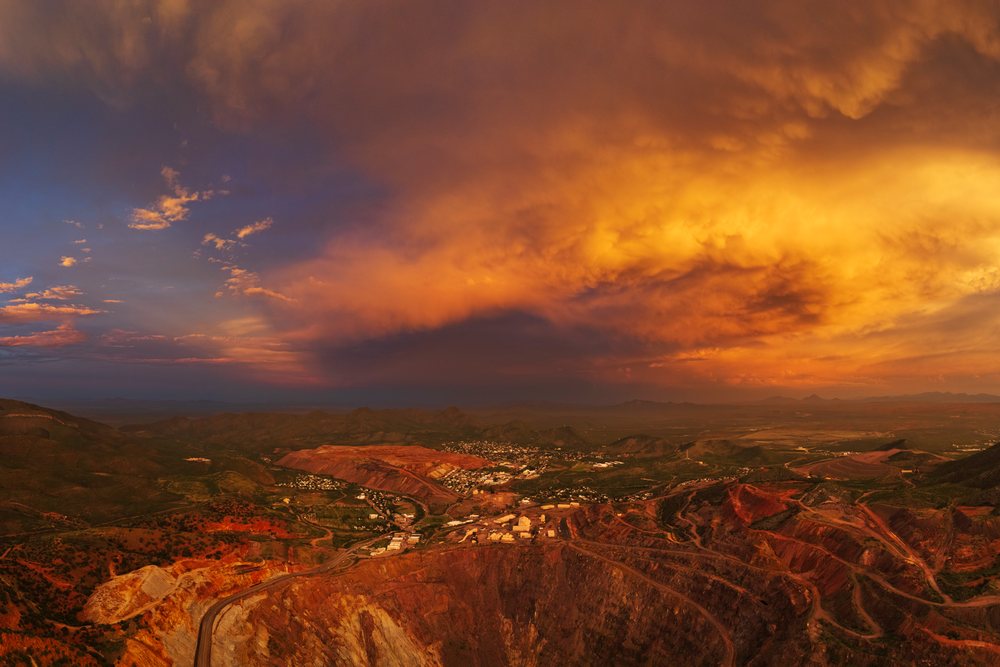 Bisbee copper mine's large open pit excavation under dramatic dusk storm clouds in mountainous Arizona landscape, Storm Chasing, Weather, Environmental Issues, USA.