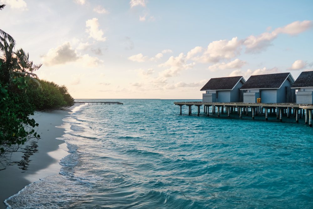 Overwater bungalows on a tropical beach at sunset in the Maldives
