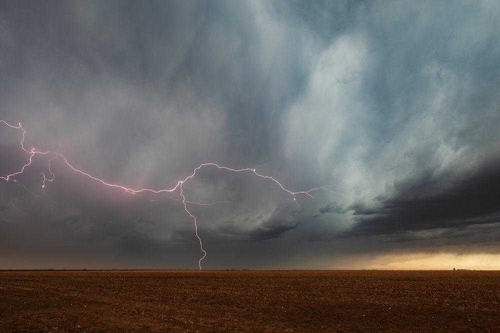 Lightning bolt strikes above a flat field under dark storm clouds, Storm Chasing, Weather, Environment, Floydada, Texas, USA.