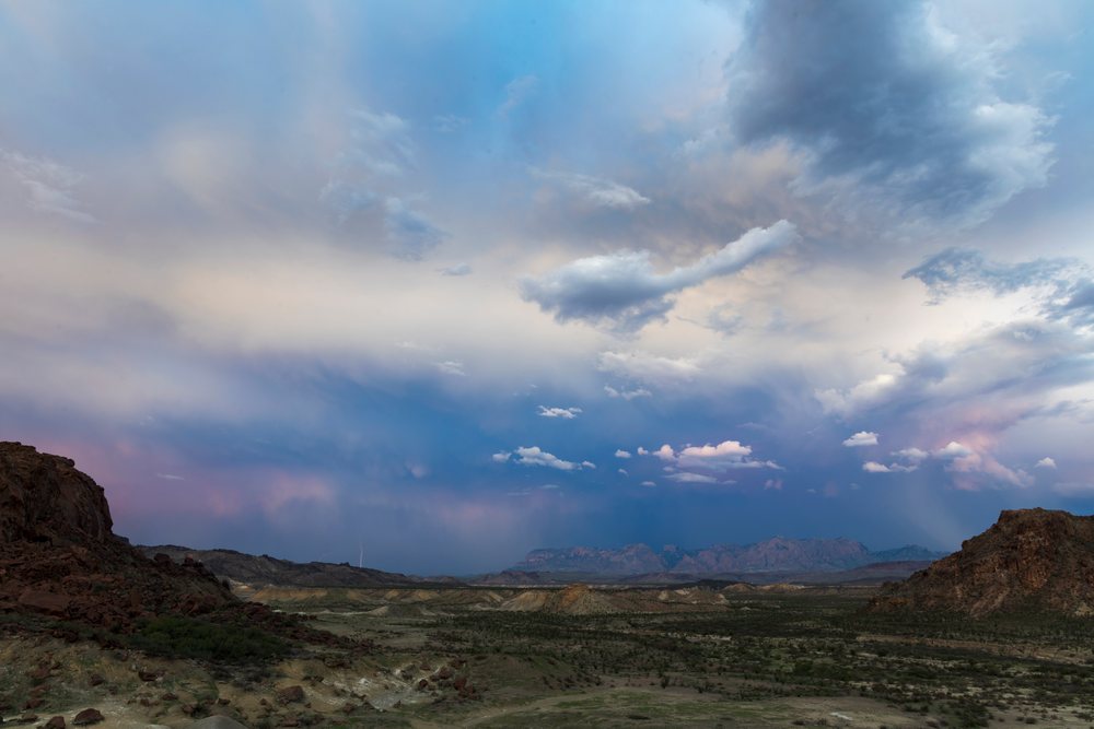 Stormy skies with visible lightning over the rocky desert terrain and sparse vegetation of the Chisos Mountains landscape, Study Butte, Texas, USA.