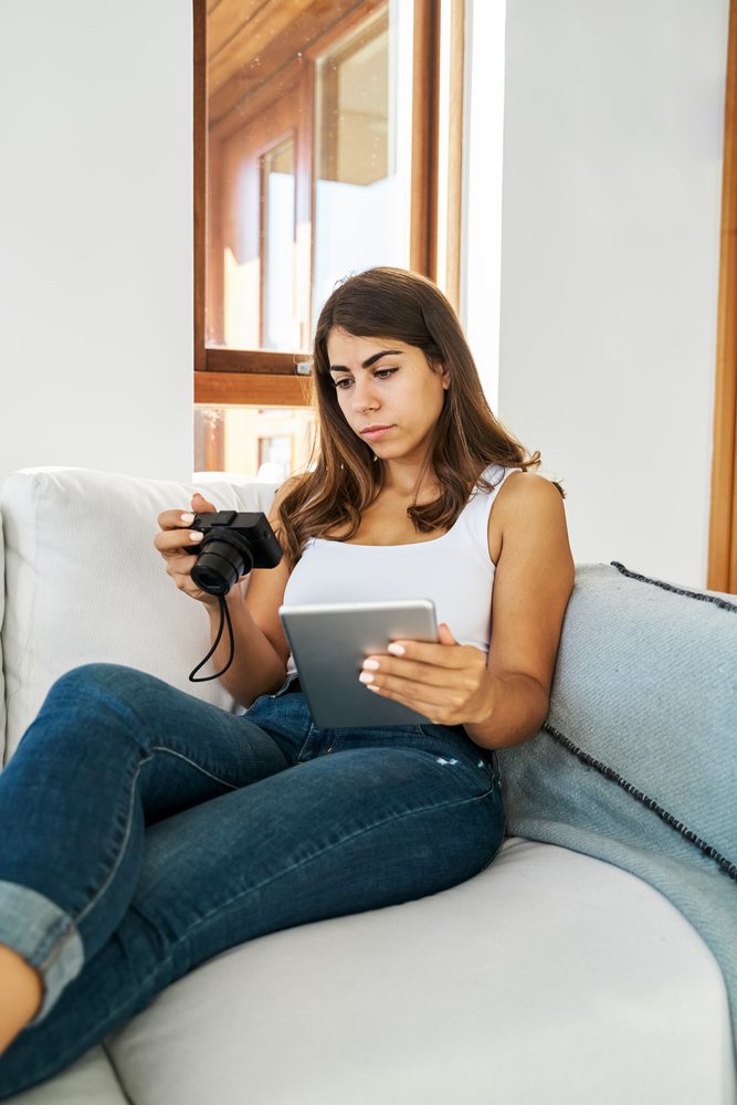 A white woman using a tablet and camera