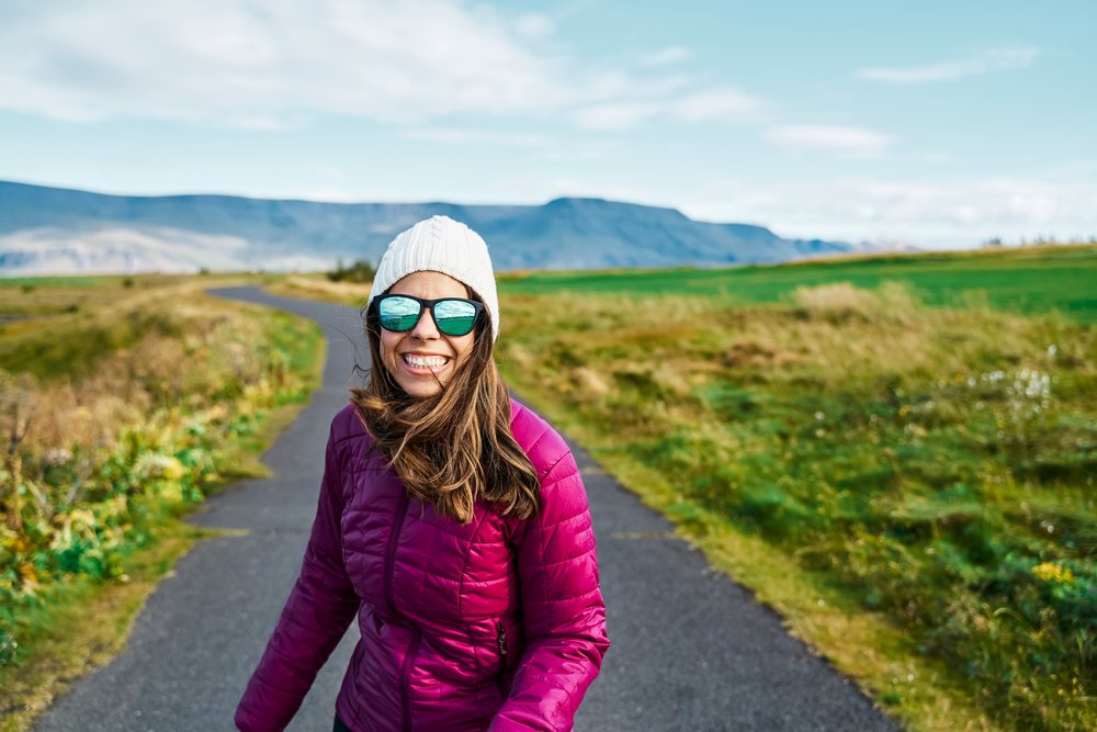 A white woman enjoys walking outdoors on a bright day