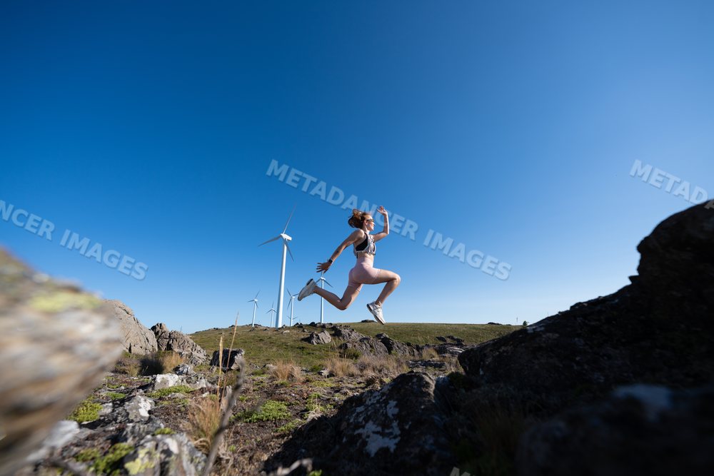 A white woman jumping energetically outdoors