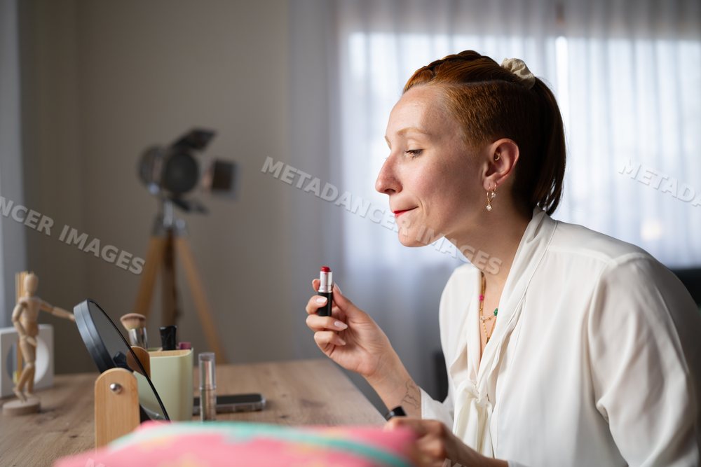 A white woman applying red lipstick
