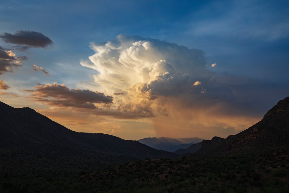 Thunderstorm cloud illuminated by Sunset light over mountains and valley with desert vegetation, Storm Chasing, Weather, Environment, Globe, Arizona, USA.
