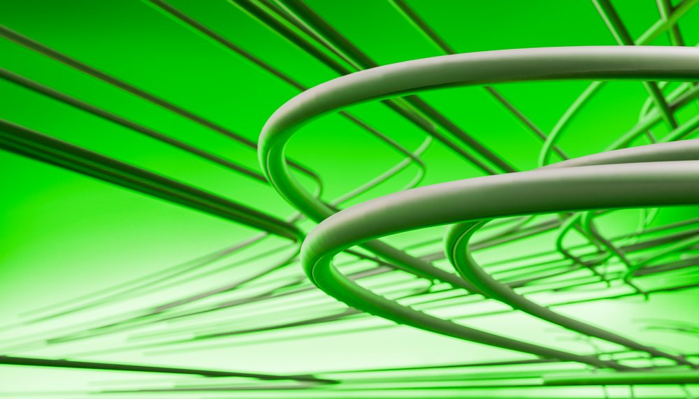 Close-up of smooth green curved cylindrical tubes forming an abstract geometric design with concentric loops.