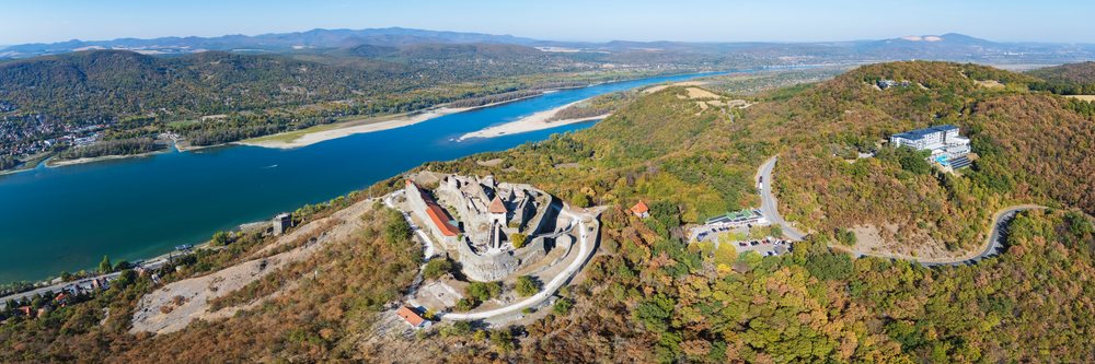 Visegrad Castle ruins atop a hill overlooking the Danube River with autumn foliage and winding roads, Cityscape, Hungary.