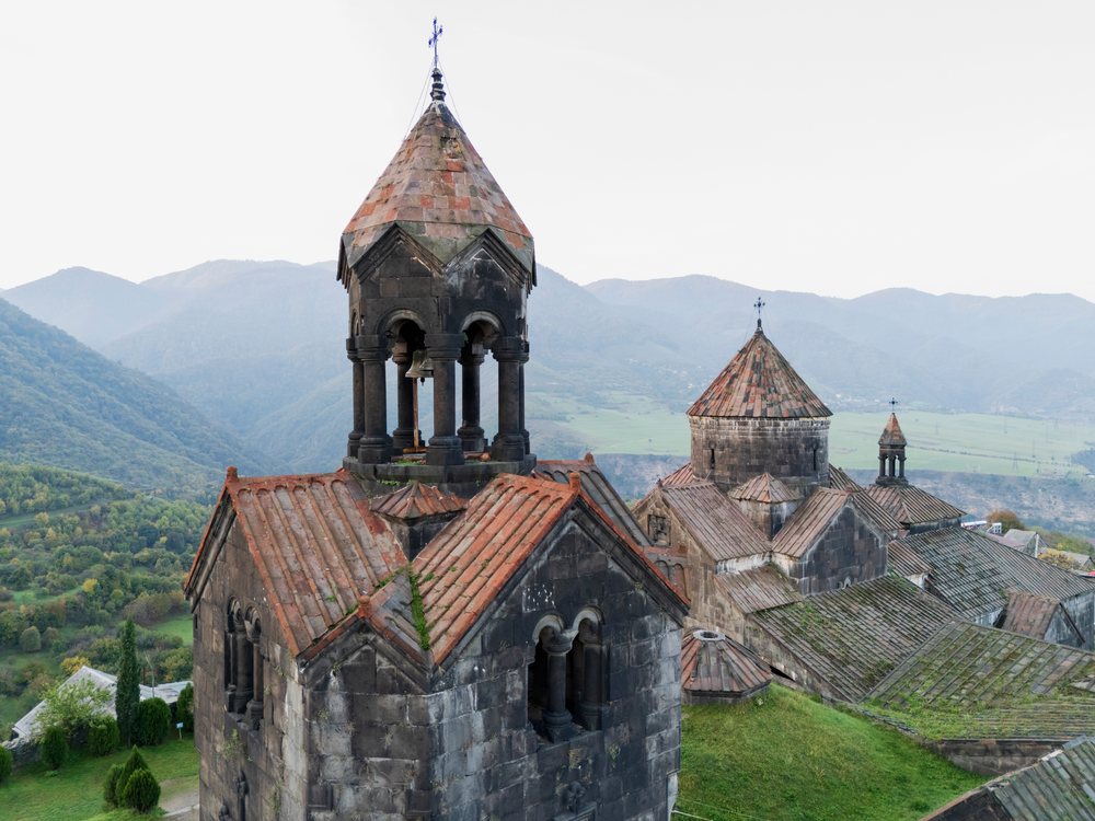Haghpat monastery with bell tower and stone churches overlooks a green valley and mountain landscape at dawn, Alaverdi, Armenia.