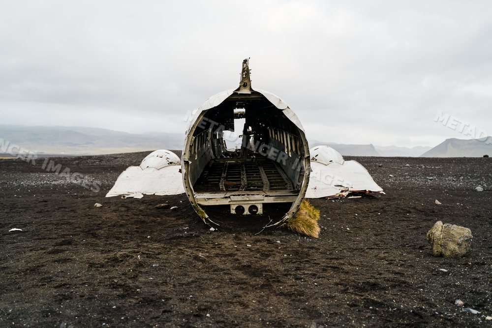 Abandoned airplane wreckage on black sandy terrain