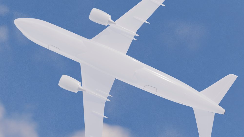 White commercial airplane flying in a blue sky with some clouds.