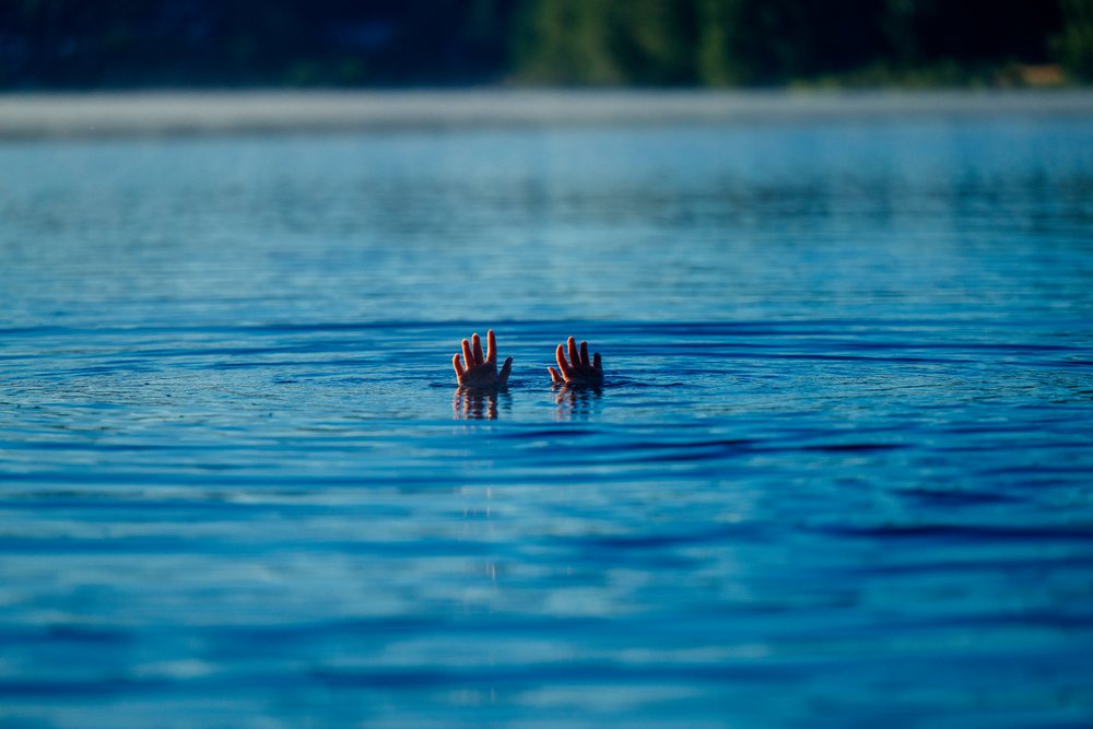 Hands raised above the surface of a calm lake with blue water and ripples, USA.