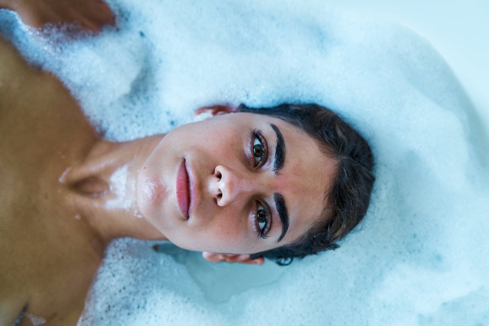 A woman relaxes in a bubble bath surrounded by foam water in the, Maldives.