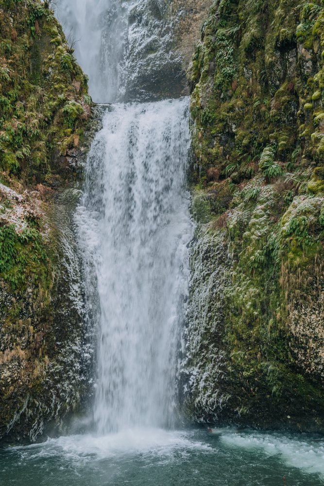 Multnomah Falls cascades down moss-covered cliffs with spray and mist, Bridal Veil, Oregon.