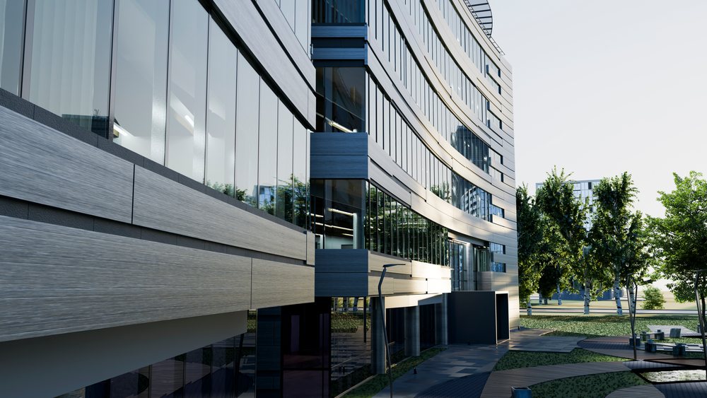 Modern office building with curved glass facade and outdoor greenery under clear daytime sky.