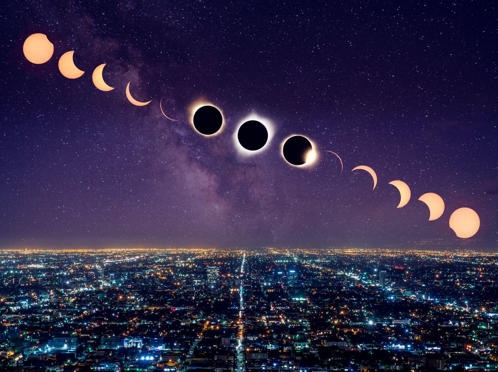Sequence of solar eclipse phases over the starry Milky Way night sky above illuminated Los Angeles cityscape, USA.