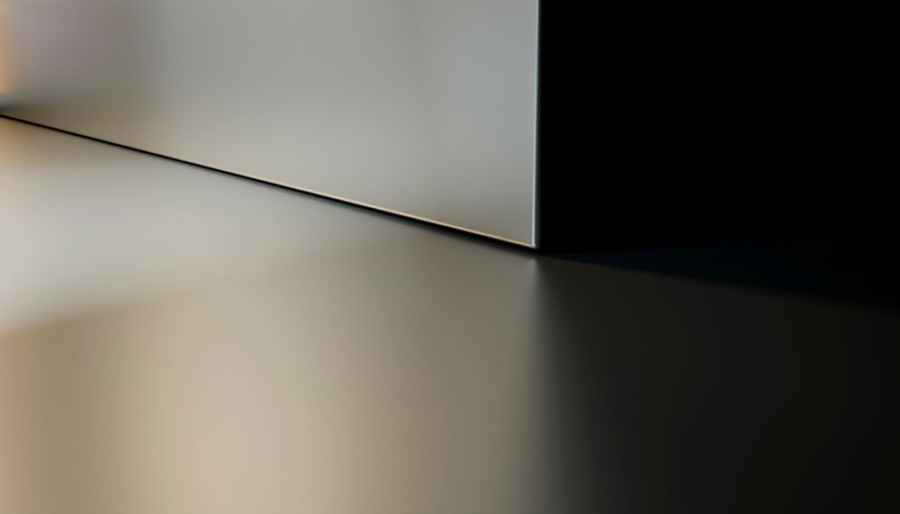 Sharp shadow cast on a clean minimalist corner of intersecting surfaces in a modern studio setting.