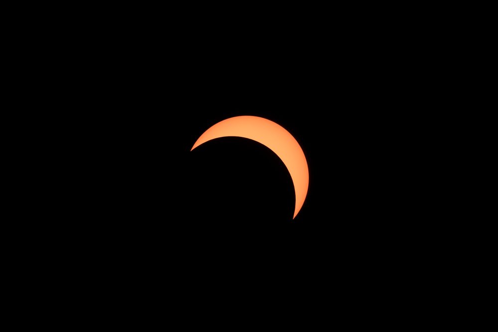 Solar eclipse shows a crescent sun silhouetted against a dark sky, Los Angeles, USA.