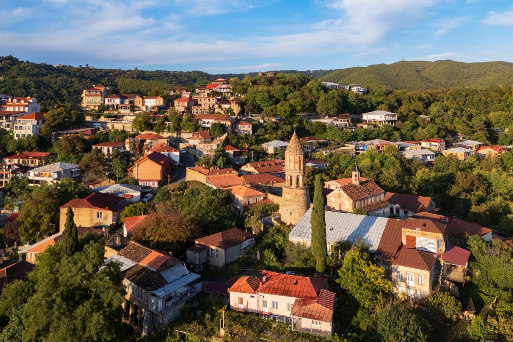 St George's Church with bell tower and village rooftops at Sunrise in hilly, Skylines, Sighnaghi, Georgia.