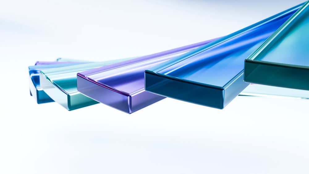 Colored transparent glass panels in blue, green, and purple stacked in an angled geometric arrangement on white background.