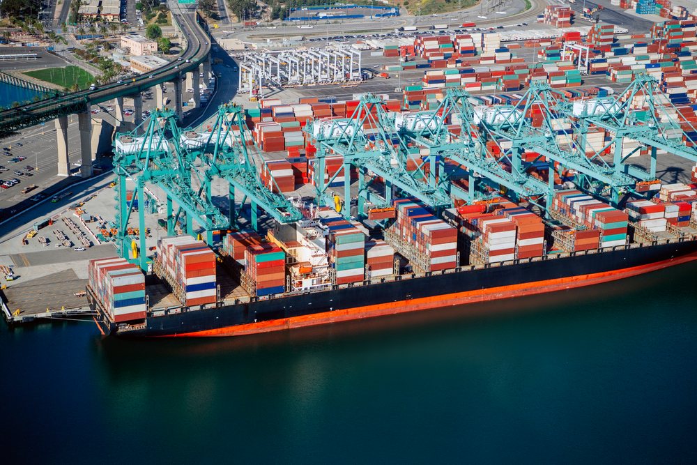 Container ship docked and loaded with cargo containers at the Port of Long Beach with multiple shipping cranes and container stacks visible, CA, USA.