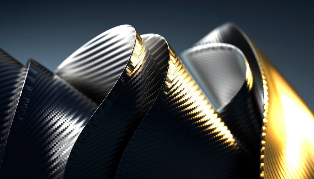Close-up of twisted carbon fiber ribbons with black and gold metallic textures against a dark background.