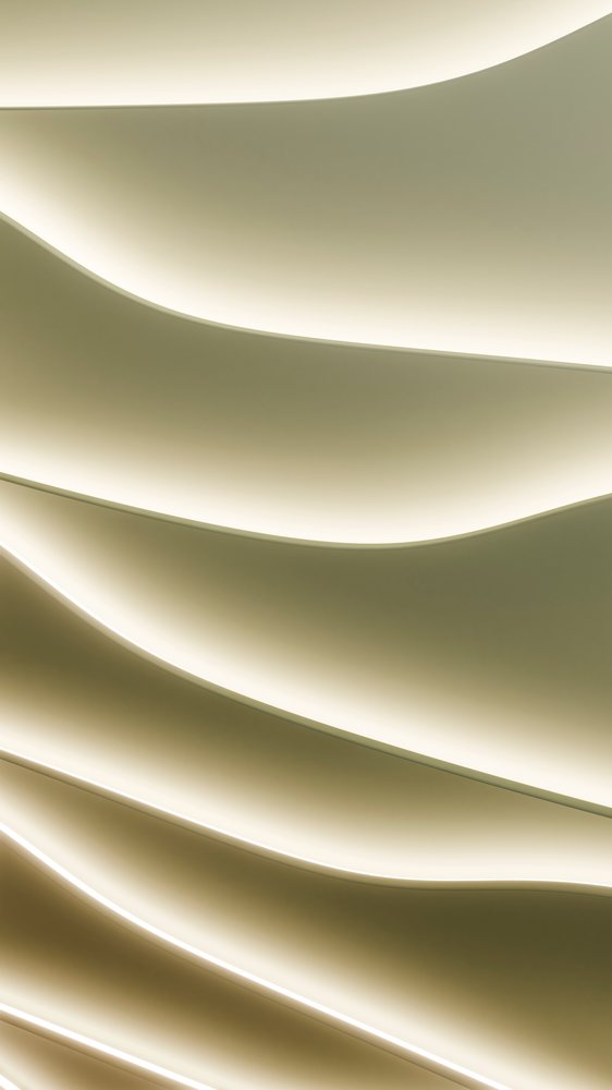 Curved ceiling panels with indirect lighting create a wave pattern in a modern architectural interior.