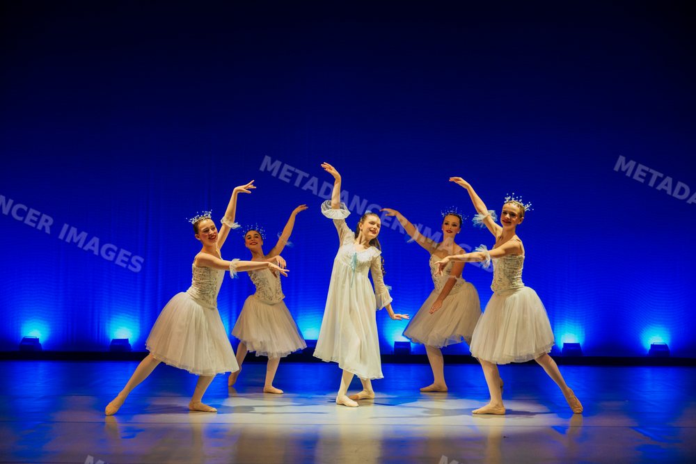 Young ballet dancers perform gracefully on stage in white costumes