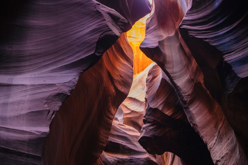 Sunlight illuminates smooth sandstone walls and natural arches inside Antelope Canyon slot canyon, Navajo Land, Arizona, USA.