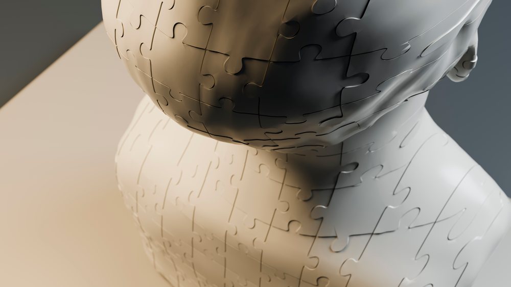 Closeup of a white jigsaw puzzle forming a human bust sculpture symbolizing conceptual thinking and mental health.