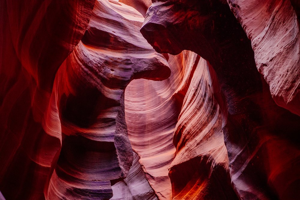 Smooth, curved red and purple rock formations inside Antelope Canyon, with natural light filtering through the slot canyon walls, Navajo Land, Arizona, USA.