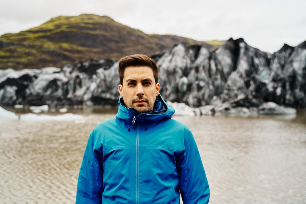 White Man standing in front of glacier waters and mountains