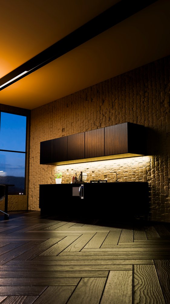 Modern kitchen interior featuring floating dark wood cabinets, under cabinet lighting, exposed brick wall, wood flooring in herringbone pattern, and a large window.