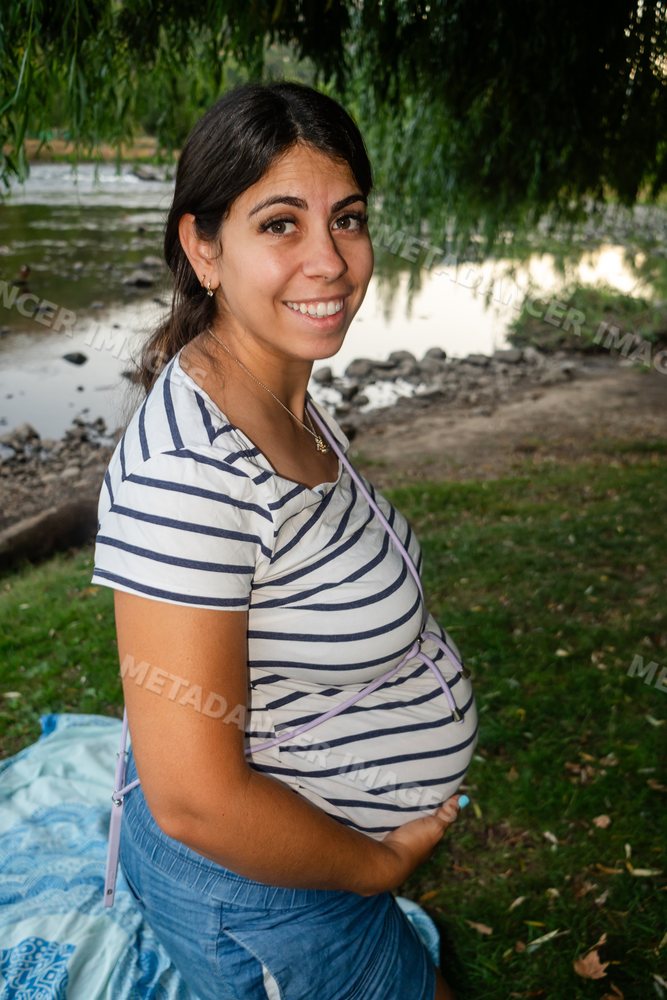 A pregnant woman enjoys outdoors by the riverside