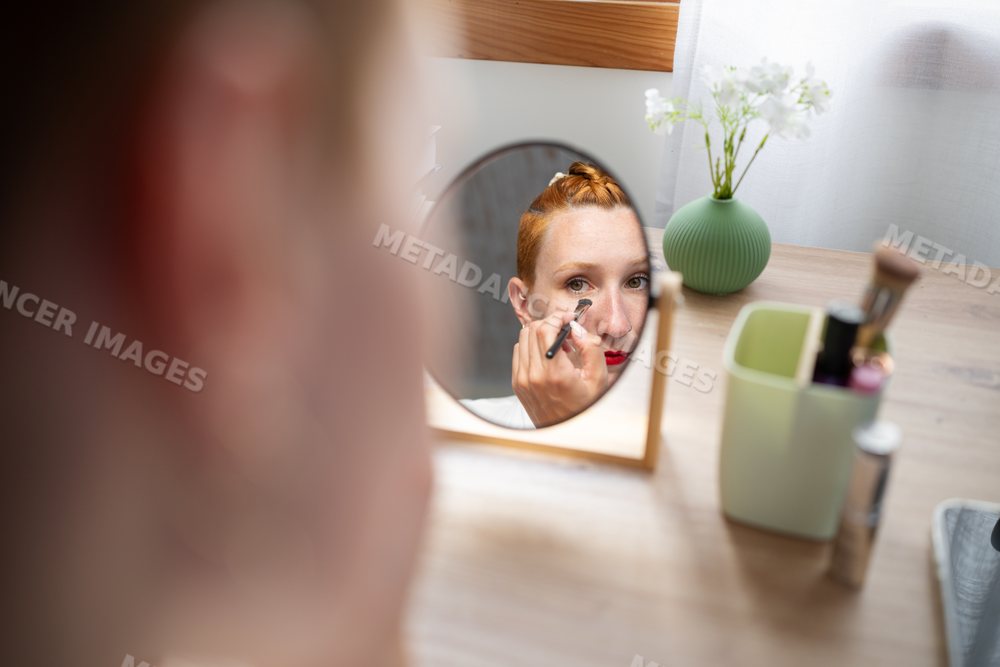 A white woman applies makeup at home in Galicia, Spain