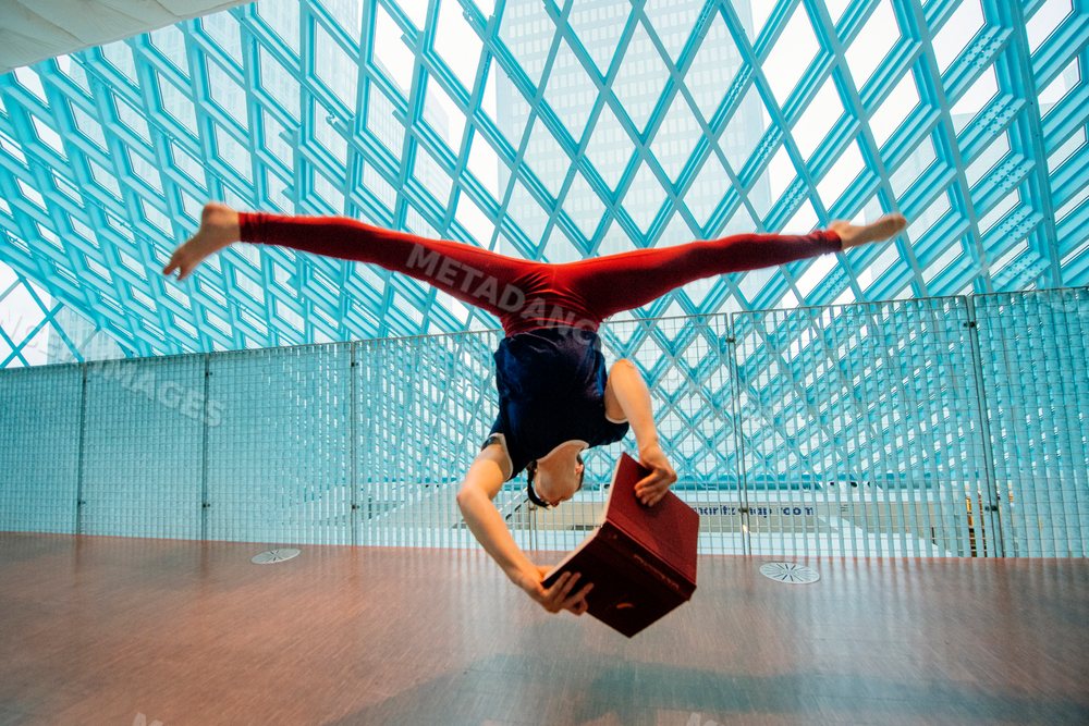 A person does a handstand reading a book inside Seattle public library